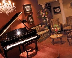a piano in a living room filled with furniture and a fire place